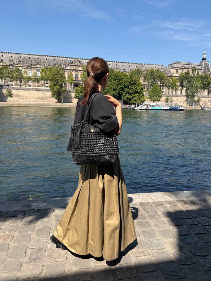 セーヌ川沿いをレザーバッグで歩く旅行中の50代女性