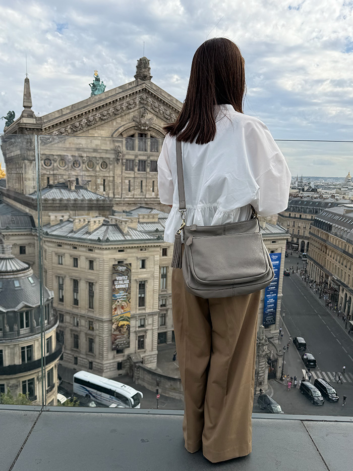 オペラ・ガルニエを見下ろす旅行中の50代女性と本革ショルダーバッグ