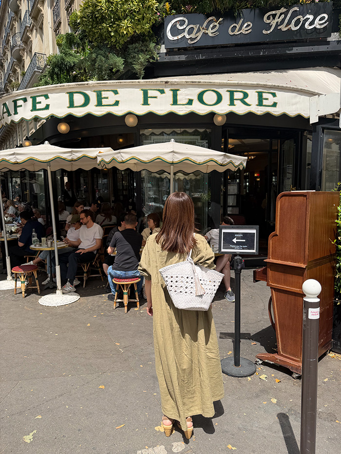 パリのカフェでショルダーバッグと過ごす旅行中の50代女性