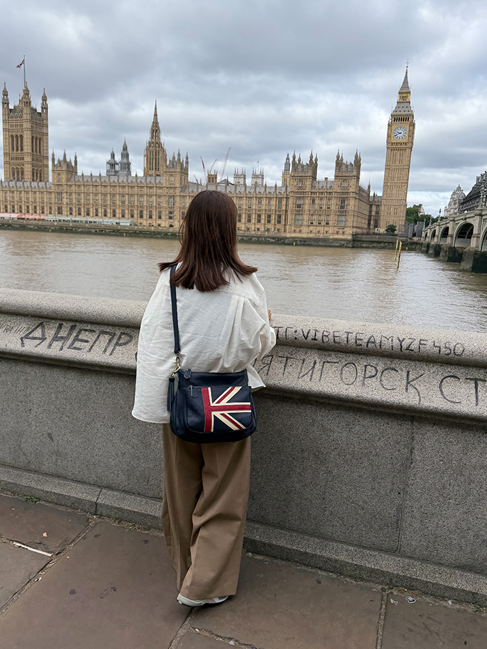 ロンドン ビックベンを本革ショルダーバッグで歩く旅行中の50代女性