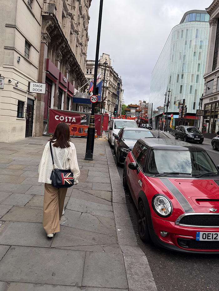 ロンドンの街をショルダーバッグで歩く旅行中の50代女性
