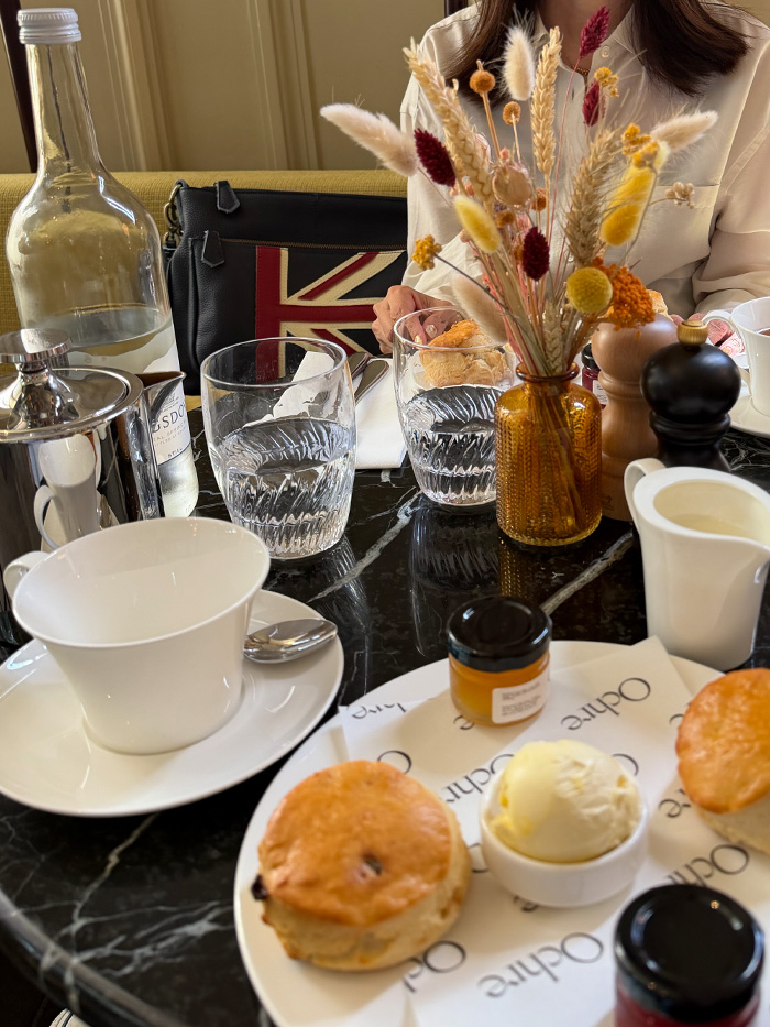 ロンドンで紅茶とカフェを楽しむ50代女性と旅行バッグ