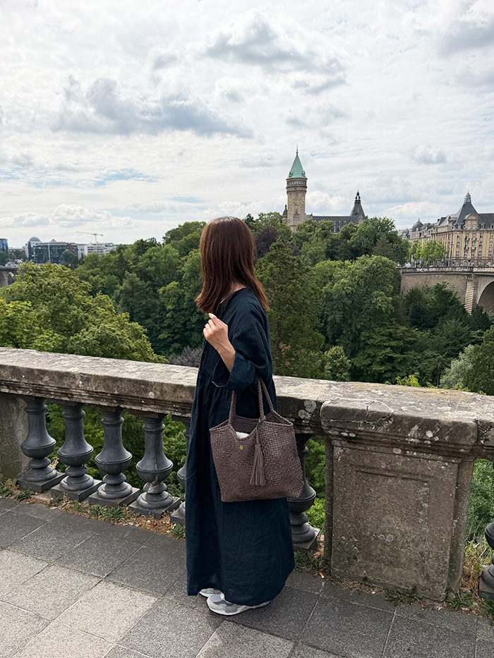 ルクセンブルクの街並みを眺める50代女性と本革旅行バッグ