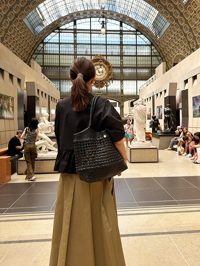 パリ旅行で美術館で本革バッグを持つ50代女性のシンプルな大人コーディネート