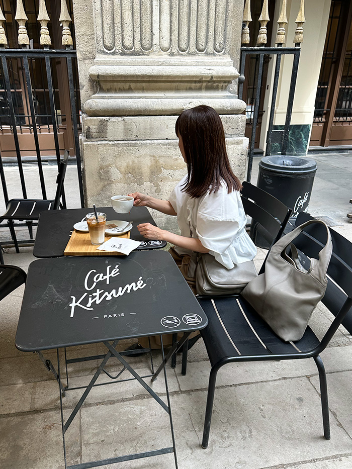 “パリのカフェで休む旅行バッグを合わせた50代女性の大人コーディネート"