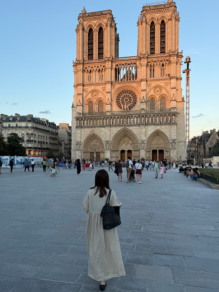 ノートルダム大聖堂を訪れる旅行中の50代女性とショルダーバッグ
