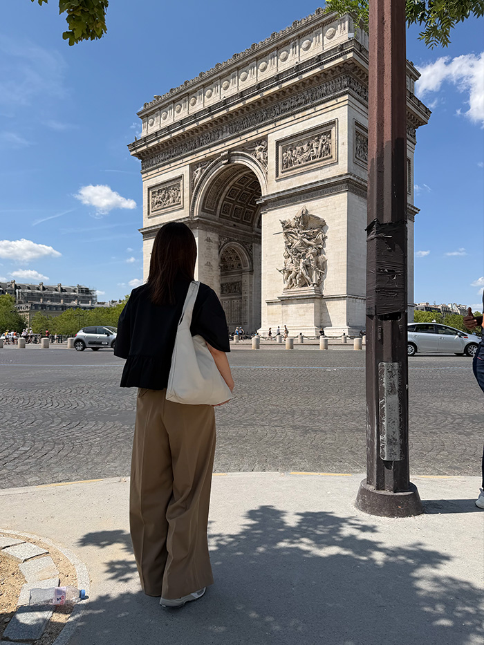 パリの凱旋門を背景にショルダーバッグで街歩きを楽しむ50代女性